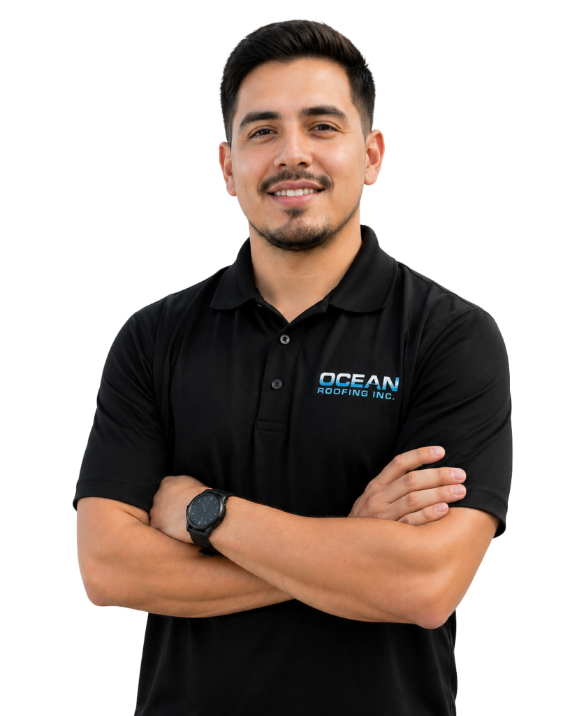 Smiling man with arms crossed, wearing a black polo shirt bearing the Ocean Roofing Inc. logo.